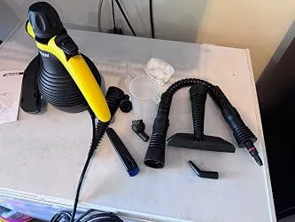 Steam cleaner with hose, brushes and nozzles laid out on a table